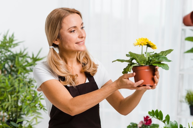 Joven mujer con delantal cuidando flores