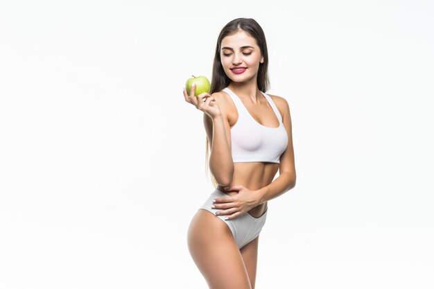 Joven mujer delgada con manzana verde. Aislado en la pared blanca Concepto de alimentación saludable y control del exceso de peso.