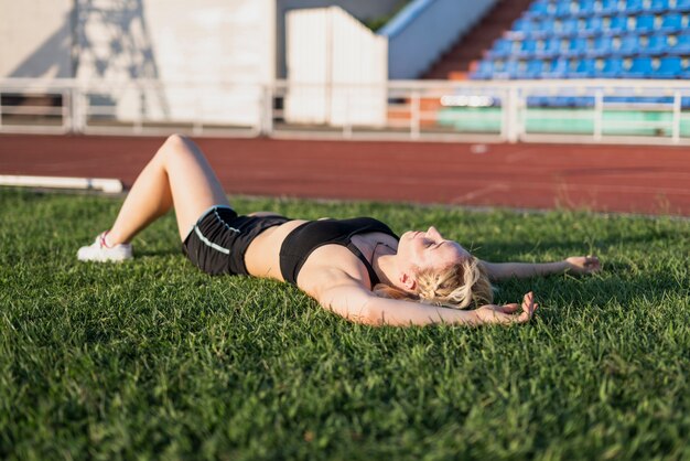 Joven mujer deportiva descanso sentado en el césped