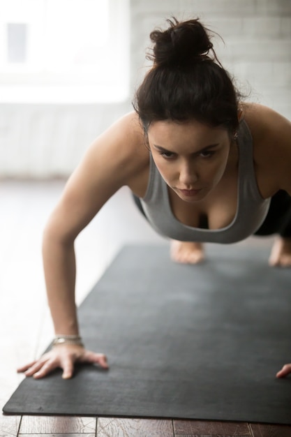 Joven mujer deportiva haciendo ejercicio de prensa ups, estudio loft blanco