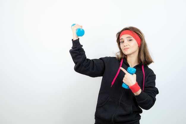 Joven mujer deportiva de pie y sosteniendo pesas azules. foto de alta calidad