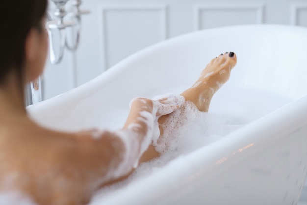 Joven mujer desnuda tomando un relajante baño espumoso