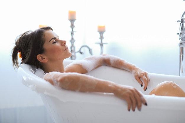 Joven mujer desnuda tomando un relajante baño espumoso