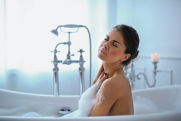 Joven mujer desnuda tomando un relajante baño espumoso