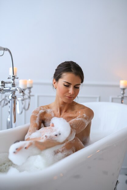 Joven mujer desnuda tomando un relajante baño espumoso