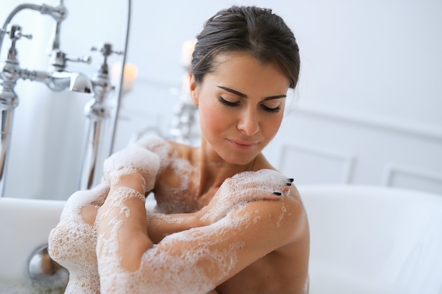 Joven mujer desnuda tomando un relajante baño espumoso