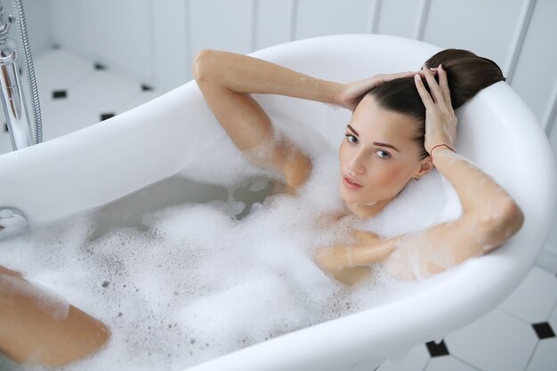 Joven mujer desnuda tomando un relajante baño espumoso