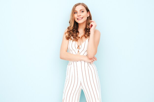 Joven mujer despreocupada posando junto a la pared azul claro en estudio