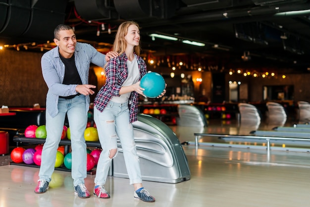 Joven y mujer divirtiéndose en un club de bolos