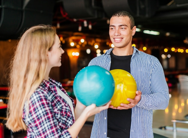 Joven y mujer divirtiéndose en un club de bolos