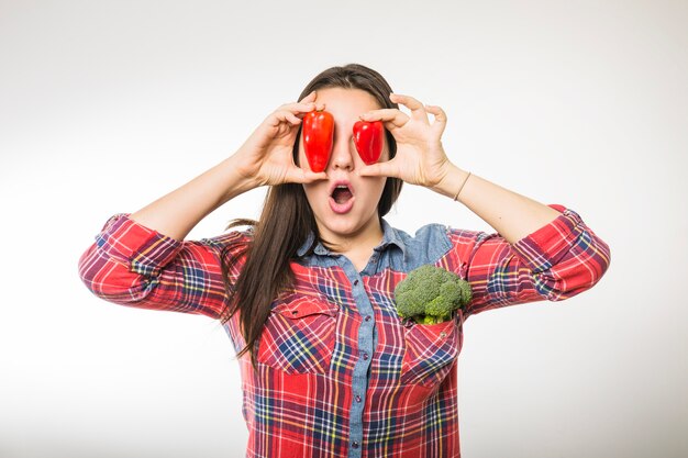 Joven mujer divirtiéndose con pimientos