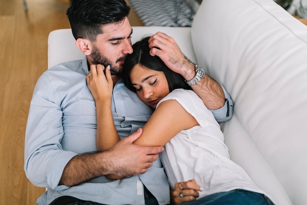 Joven mujer durmiendo con su novio en el sofá blanco