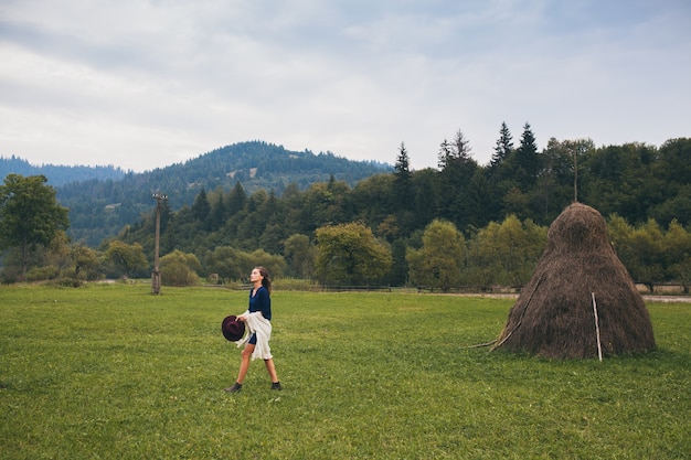 Joven mujer elegante caminando en el campo en otoño traje verde paisaje de campos y montañas