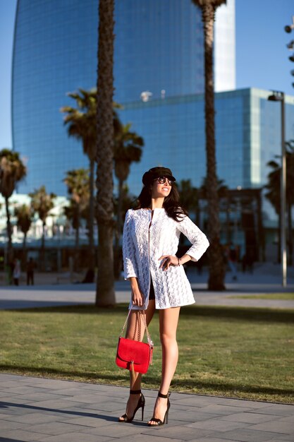 Joven mujer elegante caminando sola, atuendo elegante de moda y accesorios, dama sexy de mediana edad, colores tonificados, callejones de palmeras.