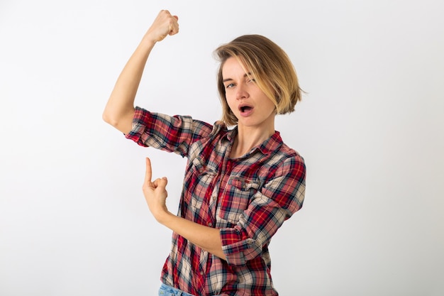 Foto gratuita joven mujer emocional bastante divertida en camisa a cuadros posando aislado en la pared blanca del estudio, mostrando gesto de fuerza