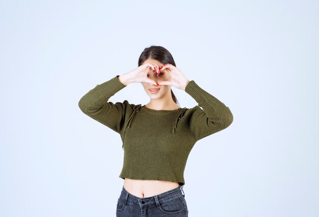 Foto gratuita una joven mujer encantadora modelo haciendo signo de corazón sobre fondo blanco.