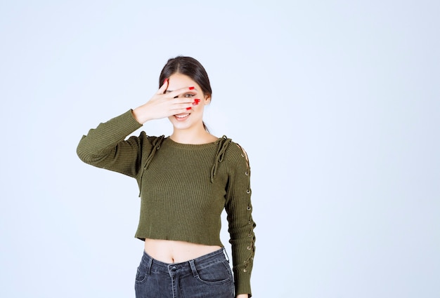 Una joven mujer encantadora modelo ocultando su rostro sobre fondo blanco.