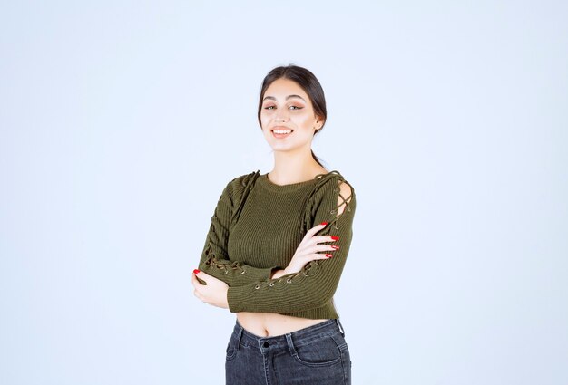 Una joven mujer encantadora modelo en verde de pie con los brazos cruzados.