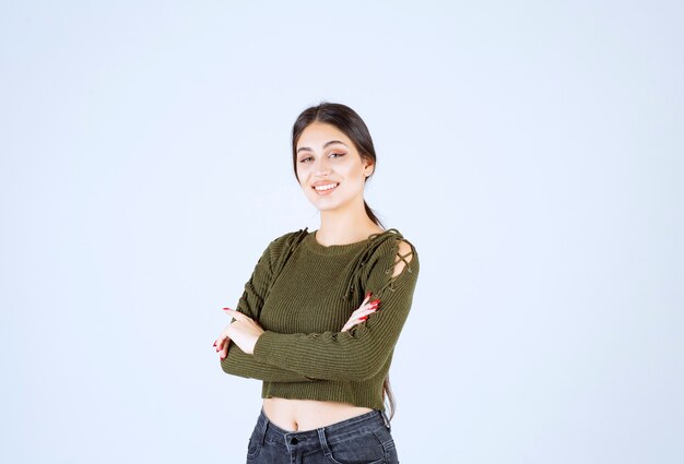 Una joven mujer encantadora modelo en verde de pie con los brazos cruzados.