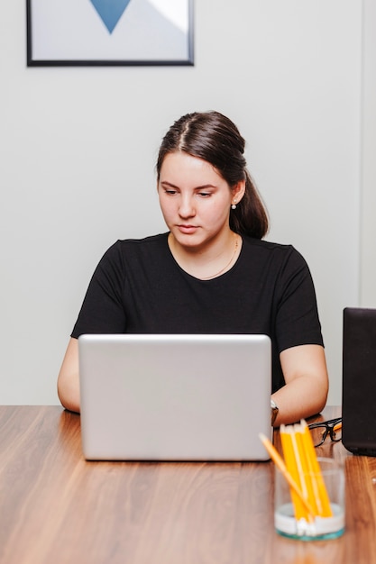 Joven mujer escribiendo portátil en la oficina