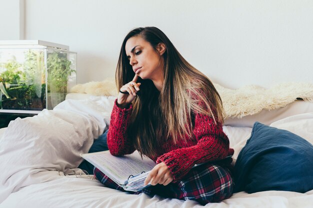 Joven mujer estudiando en la cama