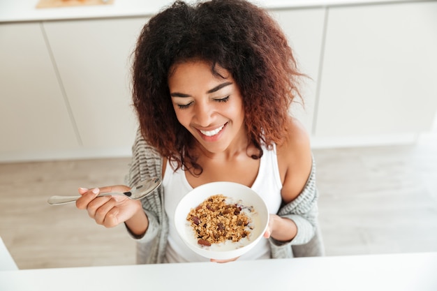 Joven mujer feliz desayunando en la cocina