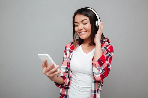 Joven mujer feliz escuchando música con auriculares.