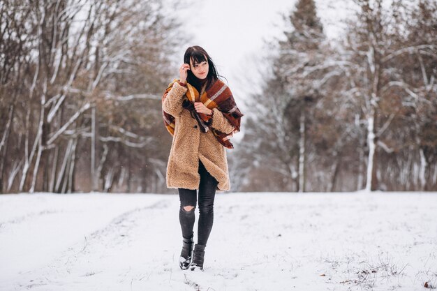 Joven mujer feliz en paños calientes en un parque de invierno