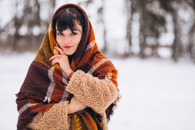 Joven mujer feliz en paños calientes en un parque de invierno