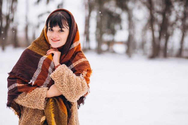 Joven mujer feliz en paños calientes en un parque de invierno
