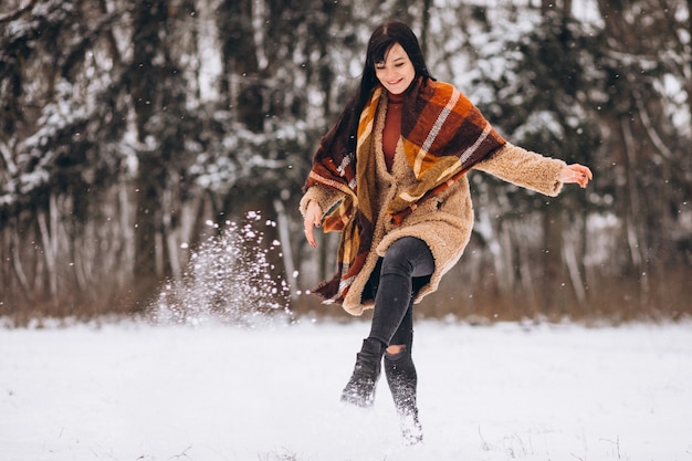 Joven mujer feliz en paños calientes en un parque de invierno