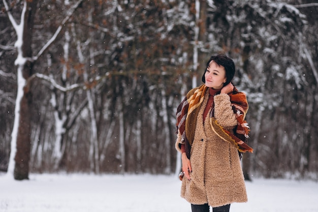 Joven mujer feliz en paños calientes en un parque de invierno