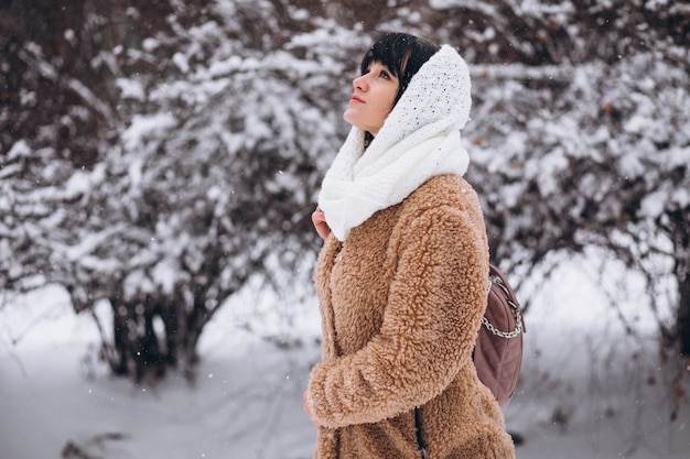 Joven mujer feliz en paños calientes en un parque de invierno