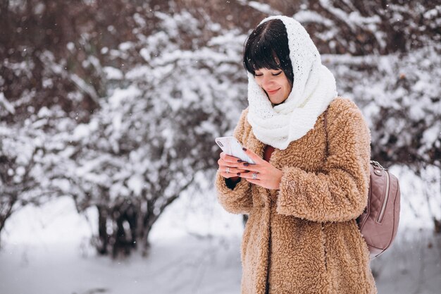 Joven mujer feliz en paños calientes en un parque de invierno