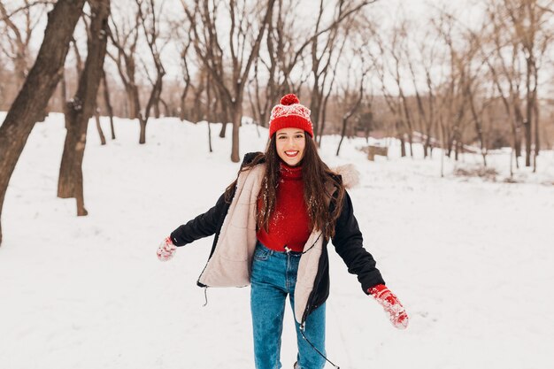 Joven mujer feliz sonriente bastante sincera en guantes rojos y sombrero con abrigo negro caminando jugando en el parque en la nieve en ropa de abrigo, divirtiéndose