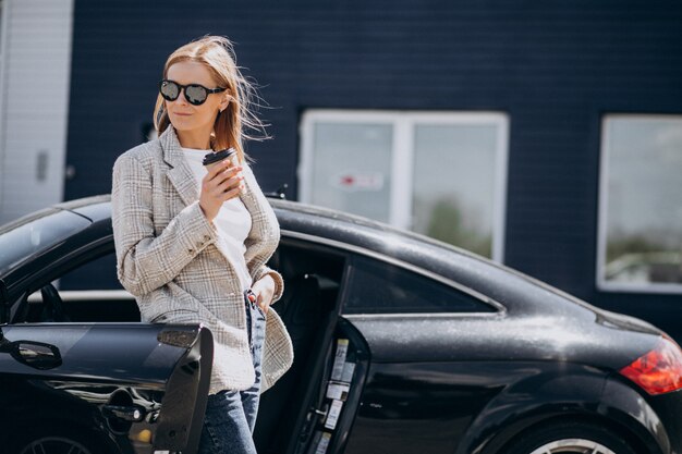 Joven mujer feliz tomando café en el coche