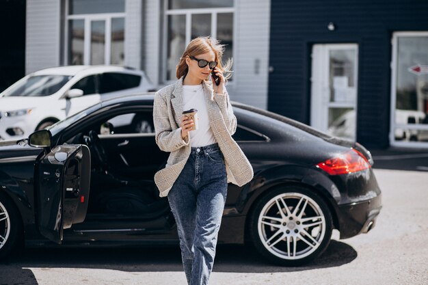 Joven mujer feliz tomando café en el coche