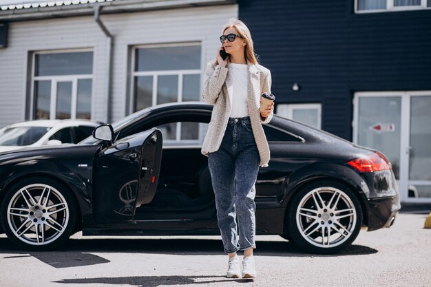 Joven mujer feliz tomando café en el coche