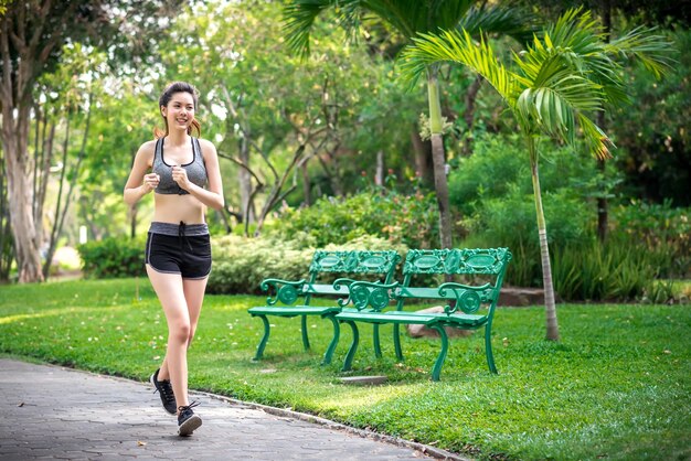 Joven mujer fitness corriendo en el parque por la mañana Deporte y concepto de estilo de vida