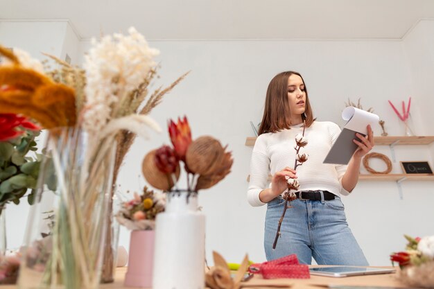 Joven mujer florista sosteniendo una flor baja vista