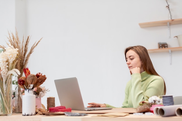 Joven mujer florista trabajando en su computadora portátil