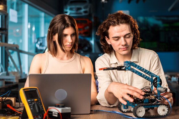 Un joven y una mujer con gafas protectoras haciendo experimentos en robótica en un laboratorio
