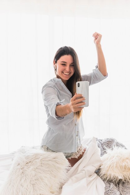 Joven mujer haciendo video llamada en teléfono inteligente bailando