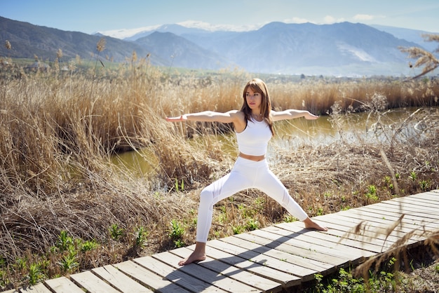 Joven mujer haciendo yoga en la playa