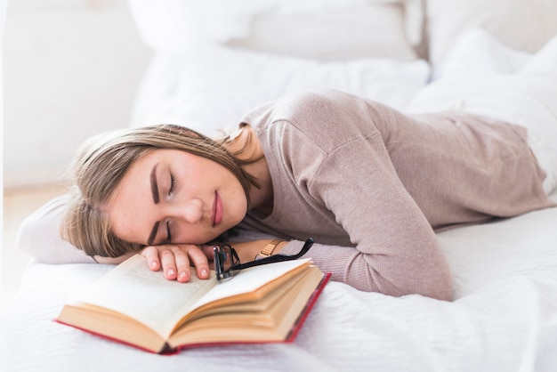 Foto gratuita joven mujer hermosa durmiendo con el libro en la cama