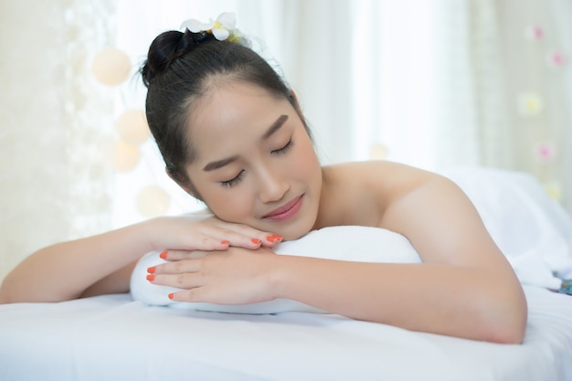 Joven mujer hermosa mentir y relajarse en el salón de spa.