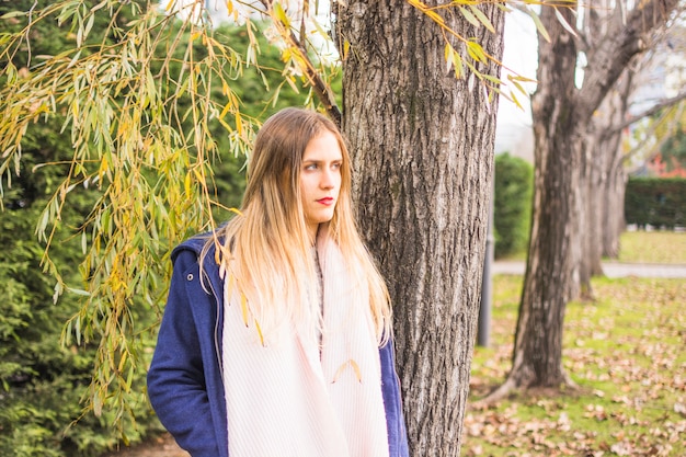 Joven mujer hermosa de pie de nuevo al parque de otoño