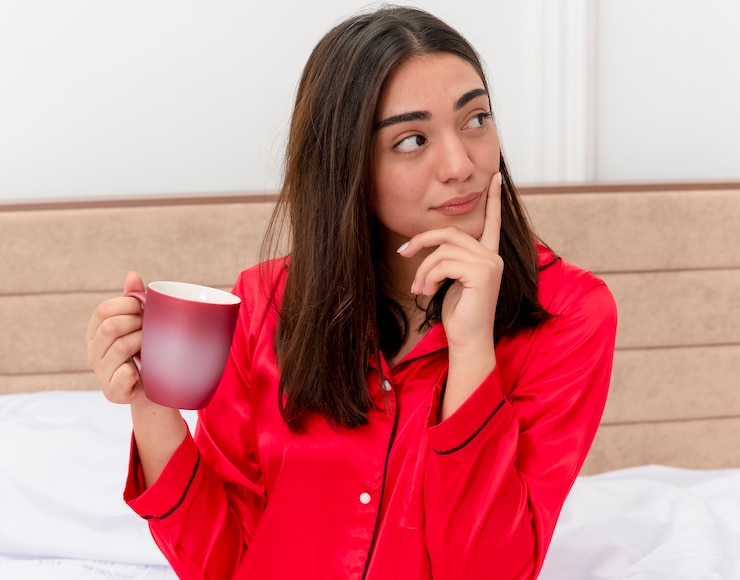 Foto gratuito joven mujer hermosa en pijama roja relajándose en la cama