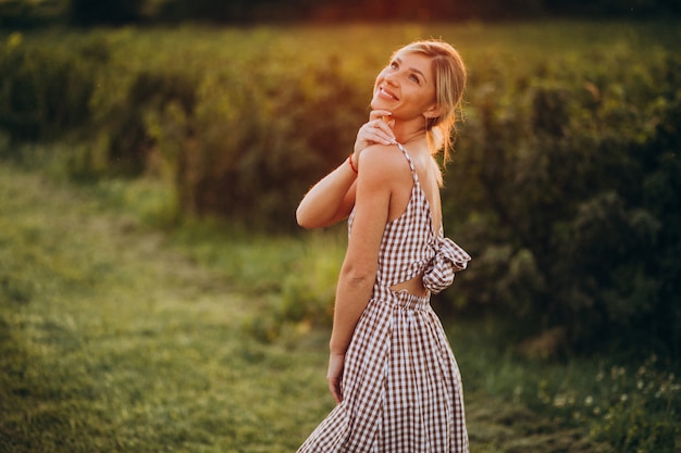 Joven mujer hermosa en la puesta de sol en el campo