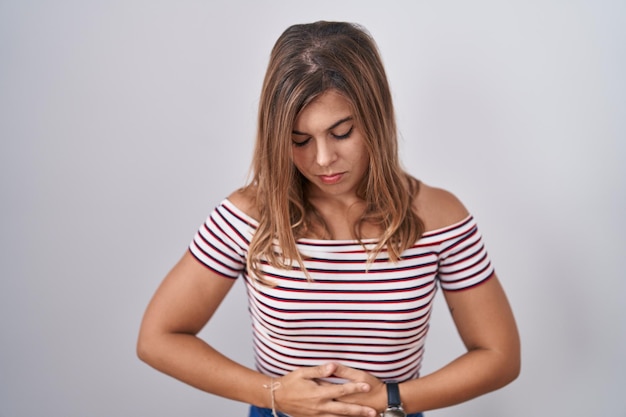 Joven mujer hispana de pie sobre un fondo aislado con la mano en el estómago porque indigestión enfermedad dolorosa sensación de malestar concepto de dolor